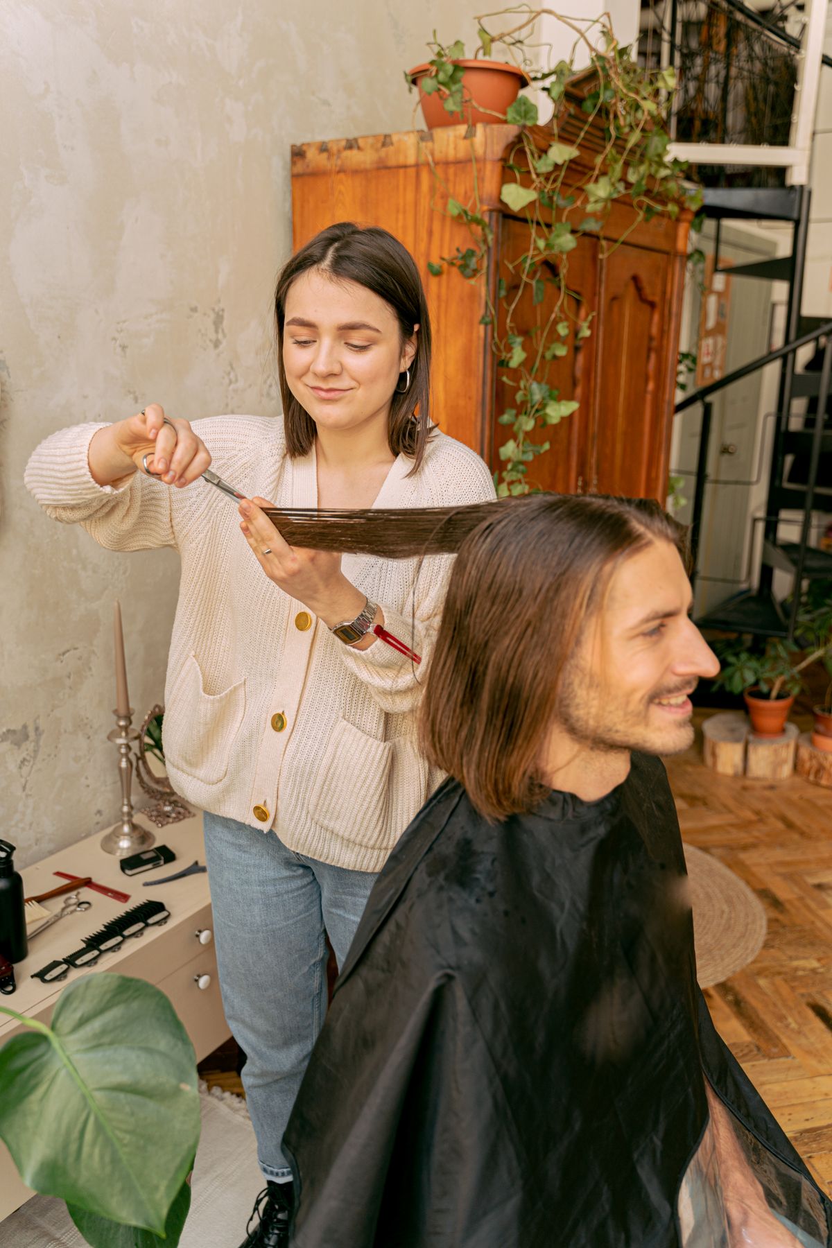 Stylist trimming a man’s long hair in a salon