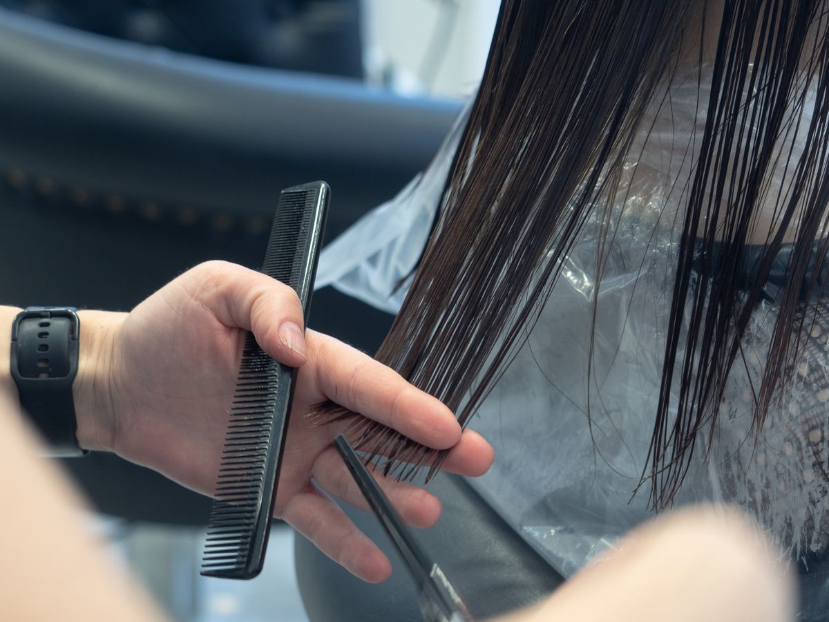Stylist trimming a client’s hair with a comb and scissors